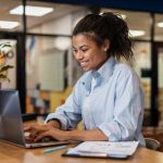 side view smiley woman working with laptop office